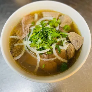 a bowl of soup with meat and onions