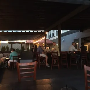 people sitting at tables under a covered patio