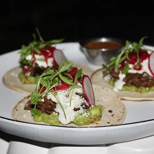 The Wagyu Short Rib Tacos are made with ancho chile, pickled onion, &amp; cotija.