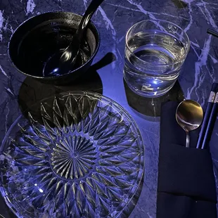 a table with a bowl of water and a plate of spoons