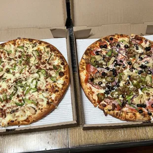 two pizzas in boxes on a table