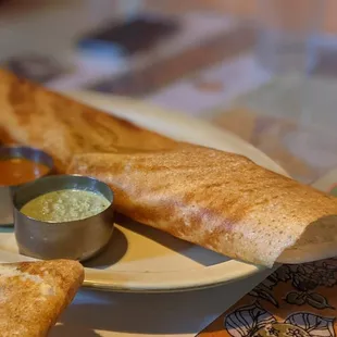 a plate of dosa and dipping sauces