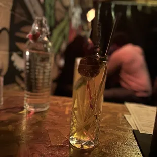 a glass of alcohol with a straw and a garnish garnish