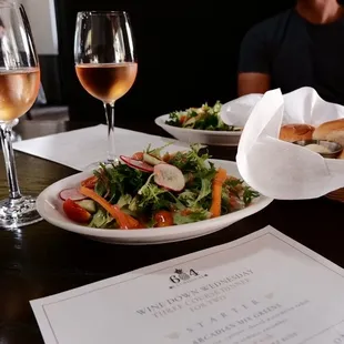 a plate of salad and two glasses of wine