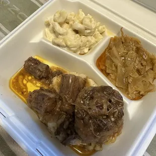 Oxtail over mashed potatoes, macaroni and cheese, and cabbage