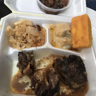 Oxtail over mashed potatoes, cabbage, mash potatoes, yams, and cornbread.