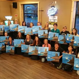 a group of people holding up their paintings