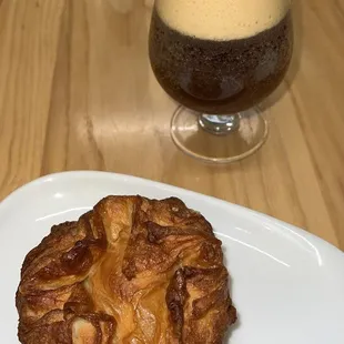 a pastry on a plate next to a glass of coffee