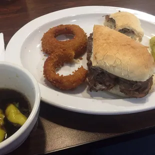 French dip with peppercini in the au jus and a side of onion rings