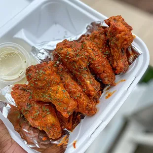 a hand holding a container of chicken wings