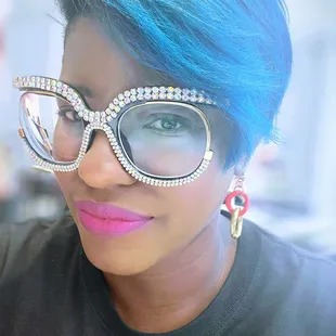 a woman with blue hair and glasses
