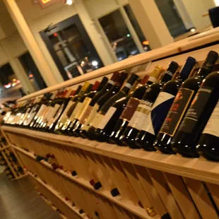 a row of wine bottles on a wooden shelf
