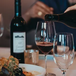 a person pouring wine into a glass