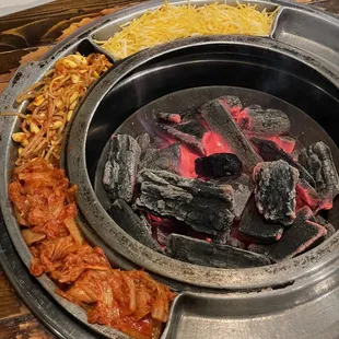 a hot pot with charcoal and vegetables