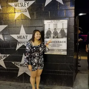 a woman standing in front of a poster