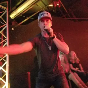 a man in a baseball cap singing into a microphone