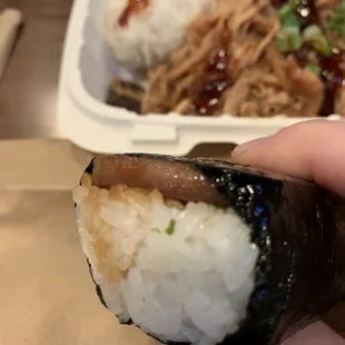 a hand holding a piece of sushi