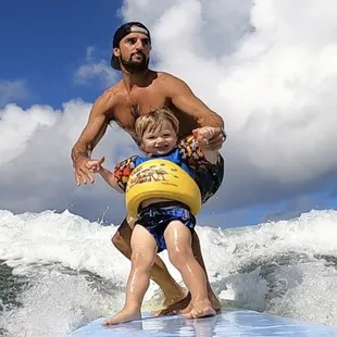 Mike of 808 Surf School surfing with his 2 year old son