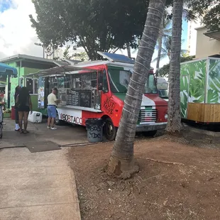 a food truck parked next to a tree