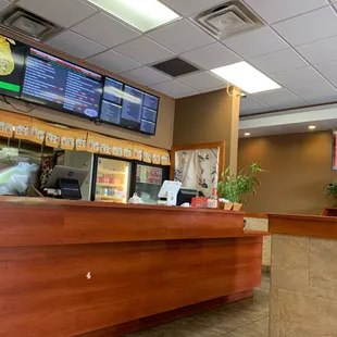 a restaurant counter with a menu on the wall