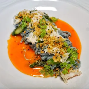 Spirulina tajarin with crab and asparagus tips in a carrot butter beurre monte sauce