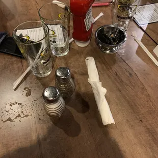 a wooden table with empty glasses and salt and pepper shakers