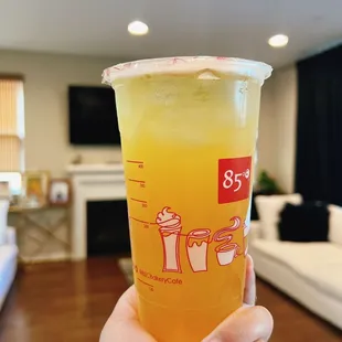  a hand holding a cup of orange juice