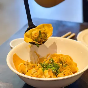 a person holding a spoon full of noodles