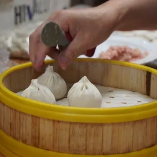 a person placing a coin into a bamboo container