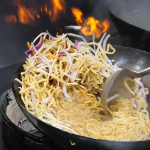 a wok of noodles being cooked in a wok
