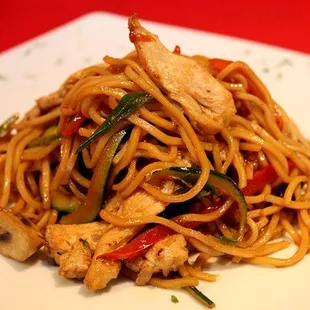 a plate of noodles with chicken and vegetables