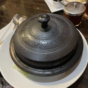 a large black pot on a white plate