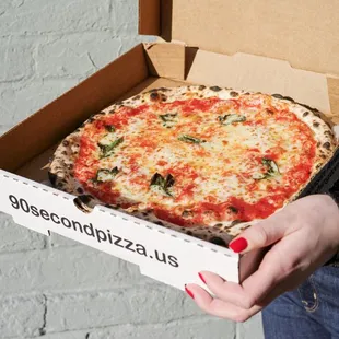 a woman holding a box of pizza