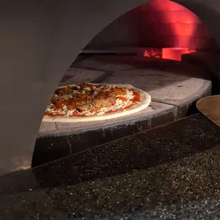 a pizza being baked in a brick oven