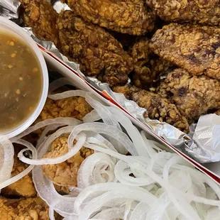 a basket of fried chicken with onions and gravy