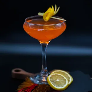 an orange cocktail with a lemon garnish