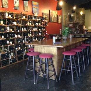 a bar with stools in front of a wall of wine bottles