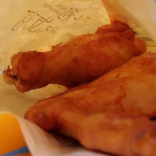 two pieces of fried chicken in a paper bag