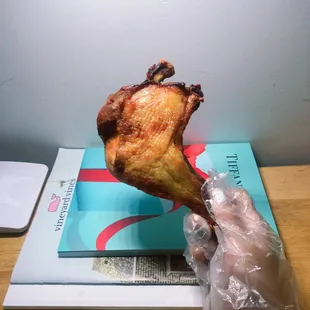 a person holding a piece of chicken