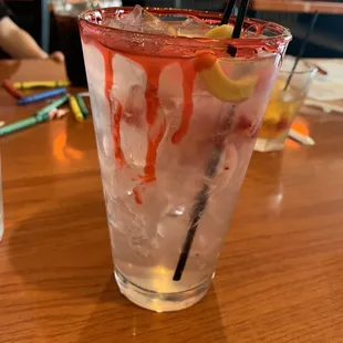a glass of ice water with a straw and a lemon slice