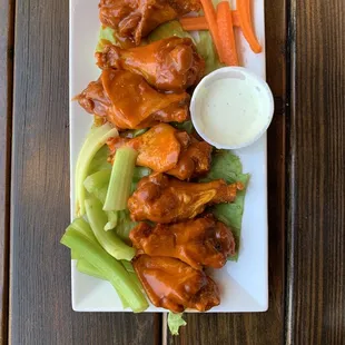 a plate of chicken wings with celery and carrots