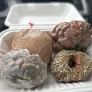 a variety of donuts in a styrofoam container