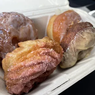 a variety of donuts in a styrofoam container