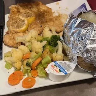 Lemon chicken with steamed vegetables, their vegetable of the day, and a baked potato