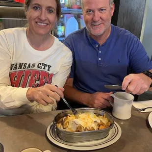 a man and a woman sitting at a table with food