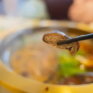 closeup of a hot pot of food with chopsticks