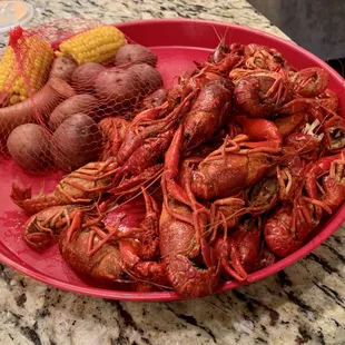 a plate of crawfish, potatoes, corn and potatoes