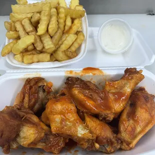 chicken wings and french fries in a styrofoam container