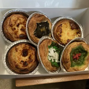 Six portugese egg tarts in a box of varying flavors (vanilla, black sesame, matcha, pandan, and durian)