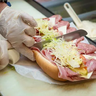 a person cutting a sub sandwich